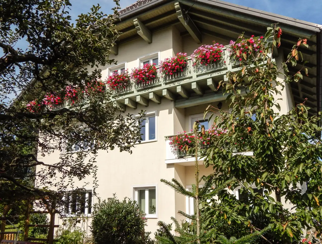 Balkoni hiše, polni rožnatih in rdečih pelargonij